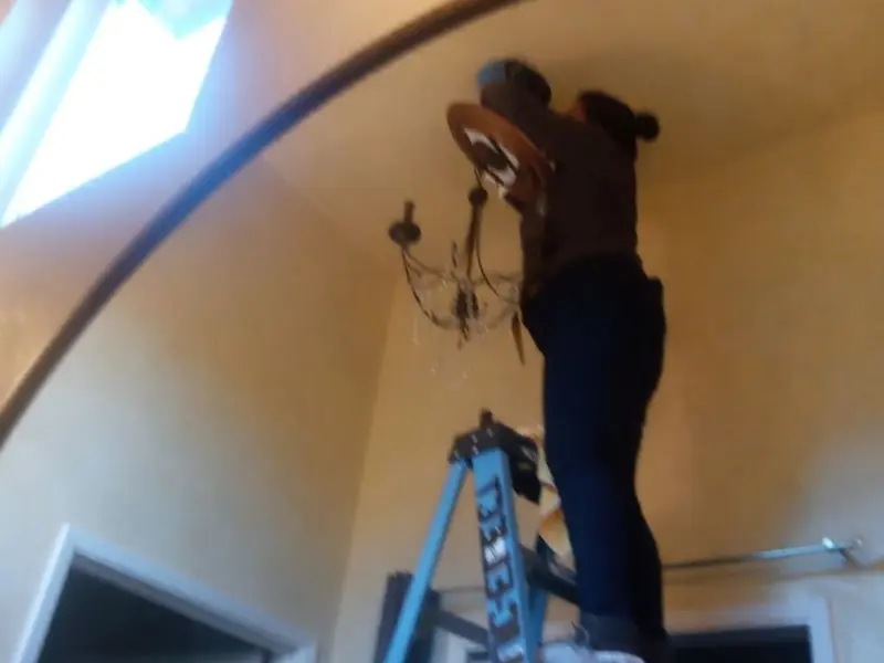 Electrician installing a chandelier in a Abbeville residence